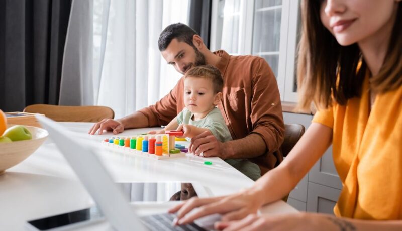 Man and kid playing educational game near mother using laptop